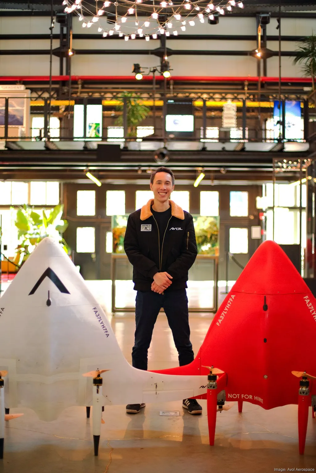 An Avol team member standing between two aircraft designs.