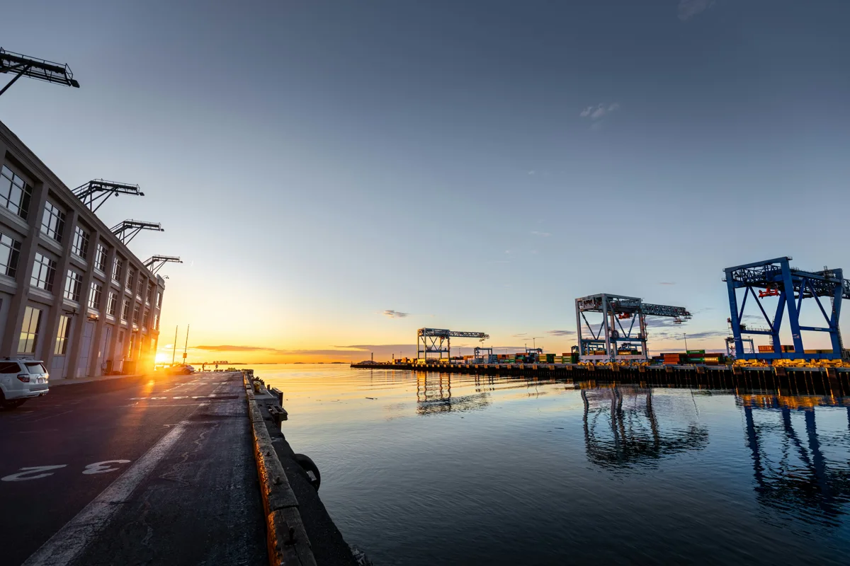 Port cranes beside a waterfront at sunrise